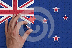 New Zealand flag is depicted on a puzzle, which the man`s hand completes to fold
