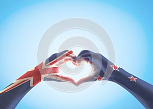 New Zealand flag pattern on people hands in heart shaped isolated on blue sky for NZ national public holiday celebration