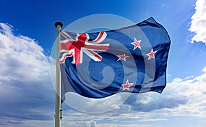 New Zealand flag waving against blue cloudy sky