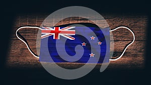 New Zealand National Flag at medical, surgical, protection mask on black wooden background. Coronavirus Covidâ€“19, Prevent