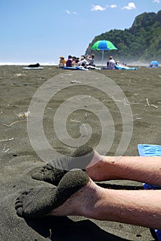 New Zealand: sandy feet on black sand beach