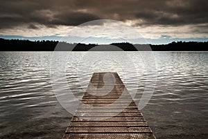 New Zealand - Wooden jetty leads into an empty lake on cloudy morning