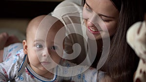 Newborn Active Baby With Young Mom. Cute Kid Smiling Teethless Face Portrait Early Days On Stomach Developing Neck