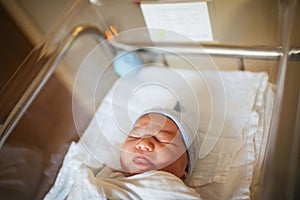 Newborn asleep in hospital bed with eyes closed