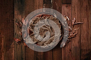 Newborn autumn background - wooden bowl with fall leaves and cream pumpkins on dark wooden planks backdrop