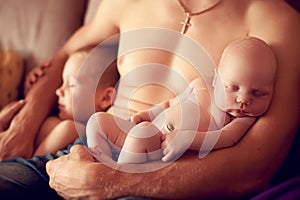 Newborn baby asleep in the arms of a strong father along with hi