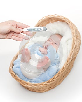 Newborn baby in basket with temperature meter