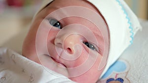 Newborn baby with big blue eyes moves his mouth and looks at the camera. Concept of caring for children. First look at