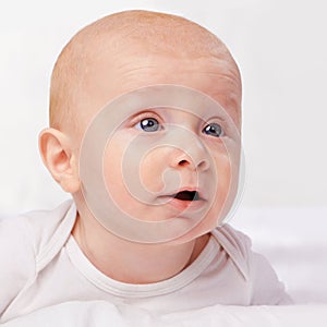 Newborn, baby and blue eyes with laying on bed for curiosity, development and growth in bedroom at house. Adorable