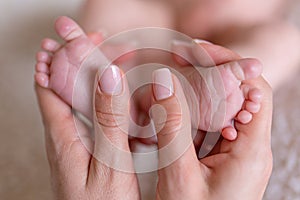 Newborn or Baby born. Child or kid feet in mother hand. New Mom or mother doing a massage. Barefoot baby