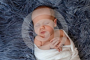 Newborn baby boy in bed. New born child sleeping under a white knitted blanket. Children sleep.