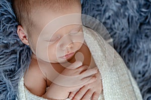 Newborn baby boy in bed. New born child sleeping under a white knitted blanket. Children sleep.