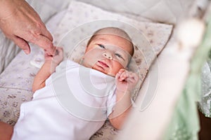 Newborn baby boy in bed. New born child in white bodykit lying in light cradle. Children sleep. Bedding for kids. Infant napping