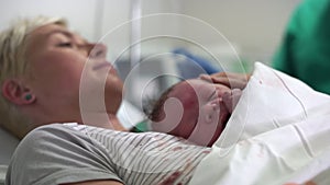 The newborn baby boy calmly lying on his mother`s chest right after birth