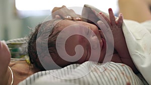 The newborn baby boy calmly lying on his mother`s chest right after birth