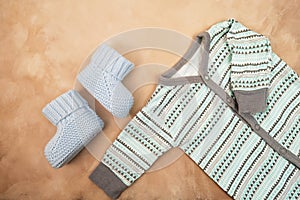 Newborn baby boy clothes. Tiny knitted booties and shirt, flatlay design. Baby`s goods.