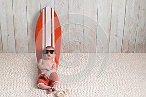 Newborn Baby Boy Leaning on Surfboard