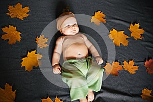 Newborn baby boy lies in autumn with maple leaves