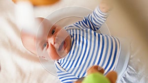 Newborn baby boy look at carousel toy spin over bed