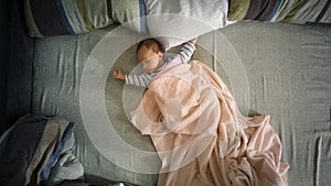 Newborn baby boy lying on big parents bed. View from top