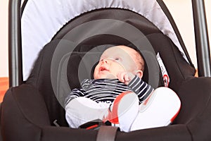 Newborn baby boy lying i car seat