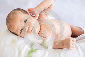 Newborn baby boy lying on white bed at home