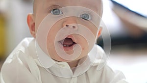 newborn baby a boy portrait close-up. little boy 6 months old looking at the camera 2 baby teeth are visible. happy