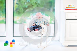 Newborn baby boy in rocking chair next window