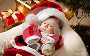Newborn baby boy in Santa clothes lying under Christmas tree