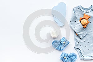 Newborn baby boy set - blue clothes as bodysuit, booties, toys - on white table top-down frame copy space