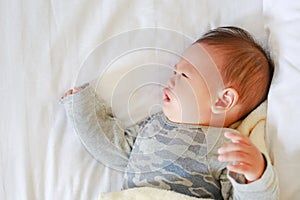 Newborn baby boy sleeping on bed with the blanket