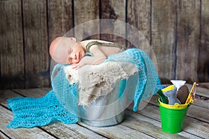 Newborn baby boy sleeping in a silver metal bucket