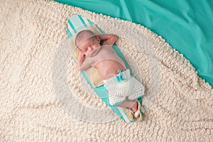 Newborn Baby Boy Sleeping on a Surfboard