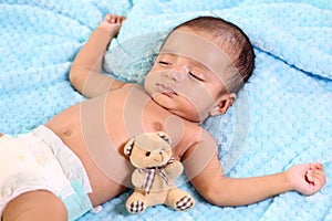 Newborn baby boy sleeping together with teddy bear