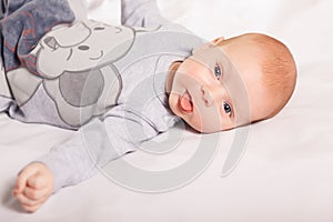 Newborn baby boy smiles lies on white background indoor. Happy, cute and pretty. Home care and cozy. Motherhood