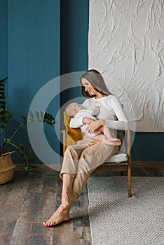 Newborn baby boy sucking milk from mothers breast. Portrait of mom and breastfeeding baby at home