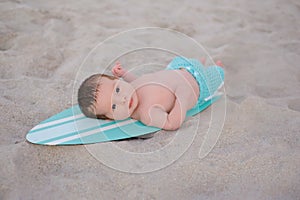Newborn Baby Boy on Surfboard in Sand
