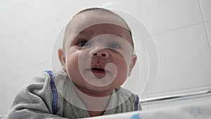 Newborn baby boy tree months old on his tummy on the baby changer smiling to camera