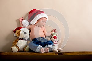 Newborn baby boy wearing a christmas hat and jeans, sleeping on