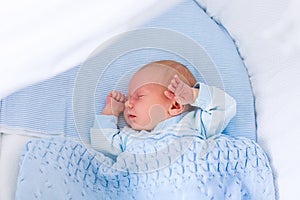 Newborn baby boy in white bassinet