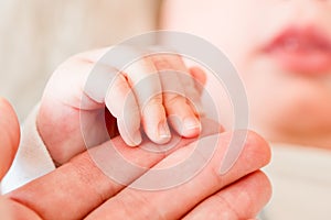 Newborn baby, closeup of fingers of fingers on hand of mother