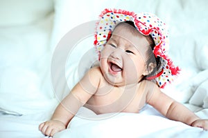 Newborn Baby with Colorful Floppy Hat Lying Down on a White Blanket