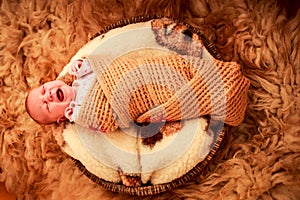 newborn baby covered in knitted scarf cries