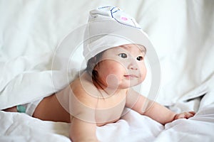 Newborn Baby with Cow Hat Lying Down on a White Blanket