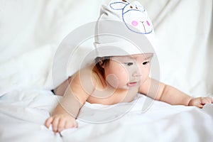 Newborn Baby with Cow Hat Lying Down on a White Blanket