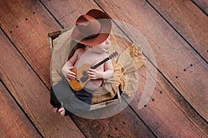 Newborn Baby Cowboy Playing a Tiny Guitar