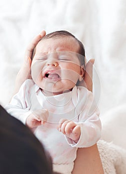 Newborn baby crying in the arms of her mother.