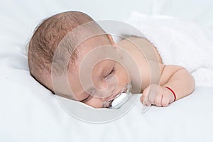 Newborn baby curled up sleeping on a blanket