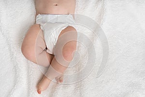 Newborn baby in diaper lying on white blanket