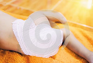 Newborn baby with Diapers - child wear white diaper and playing on a orange knitted blanket in the nursery